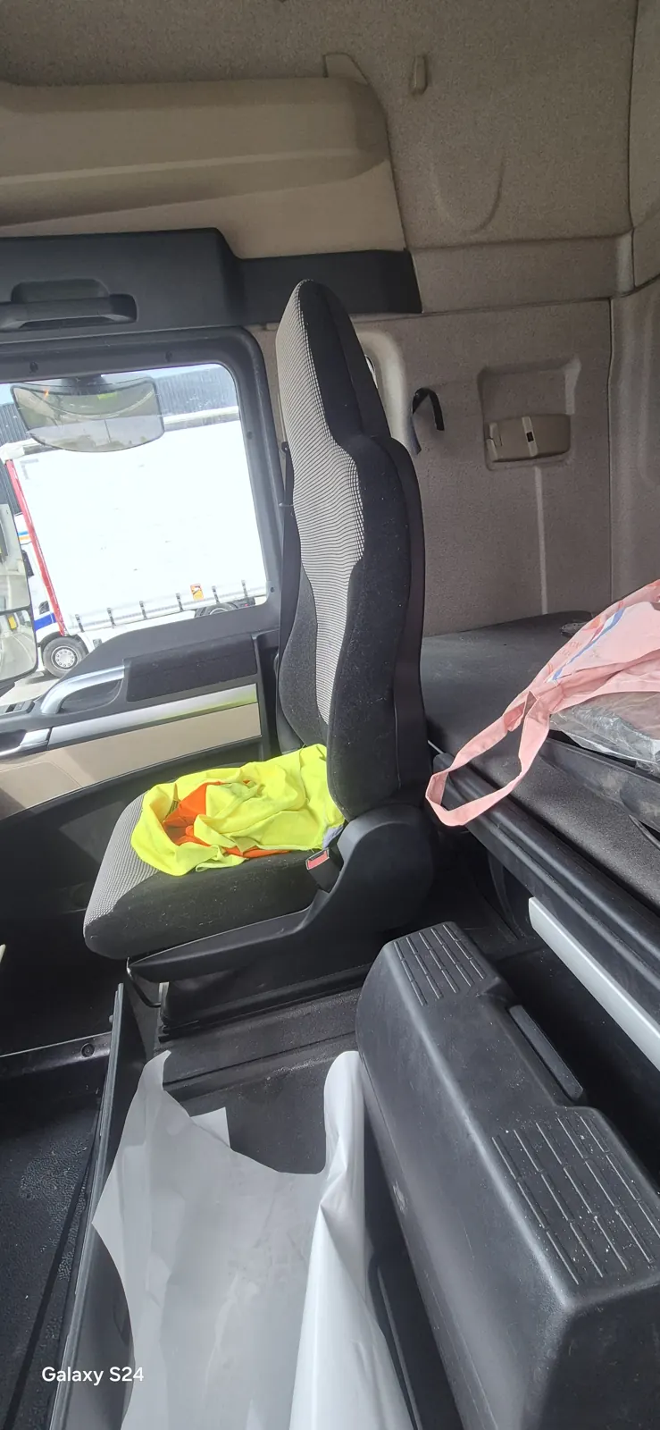 Poste passager d'une cabine de camion avant nettoyage, gilet sur le siège, sacs et plastiques au sol